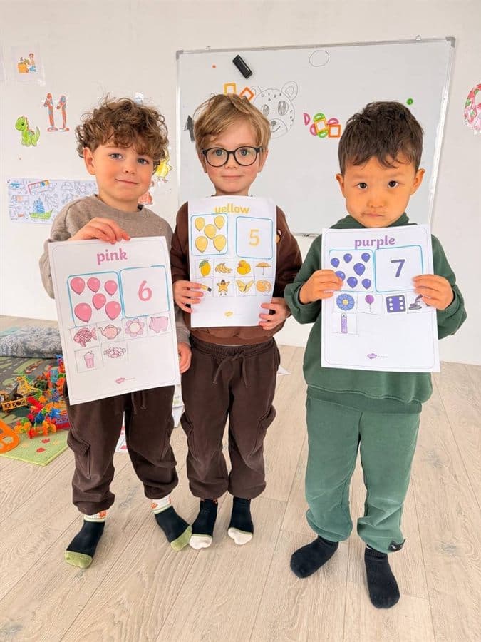 Children at EDUHUB Tbilisi holding their colour and number worksheets in class
