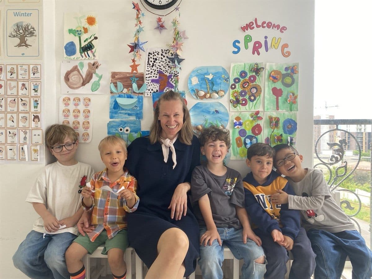 Teacher reading with a small group of children under the children's artwork display