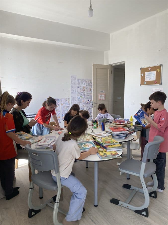Small group of children reading and drawing together at the classroom table