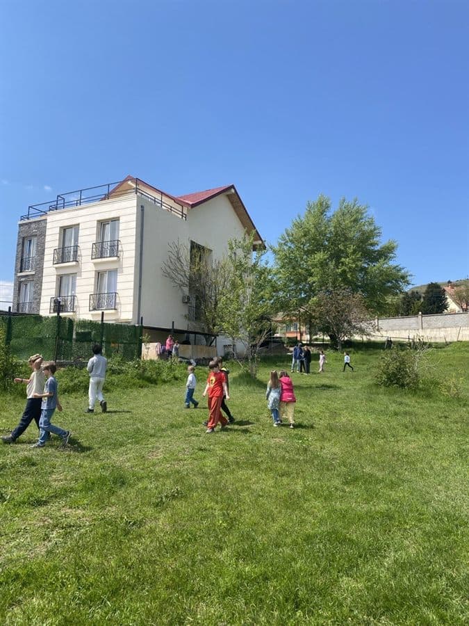 Children playing outdoors on the lawn in front of the EDUHUB learning centre